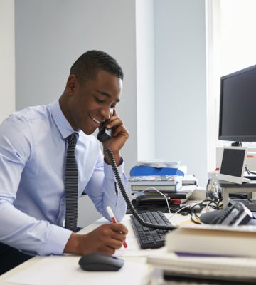 Young black businessman using the phone at his office desk